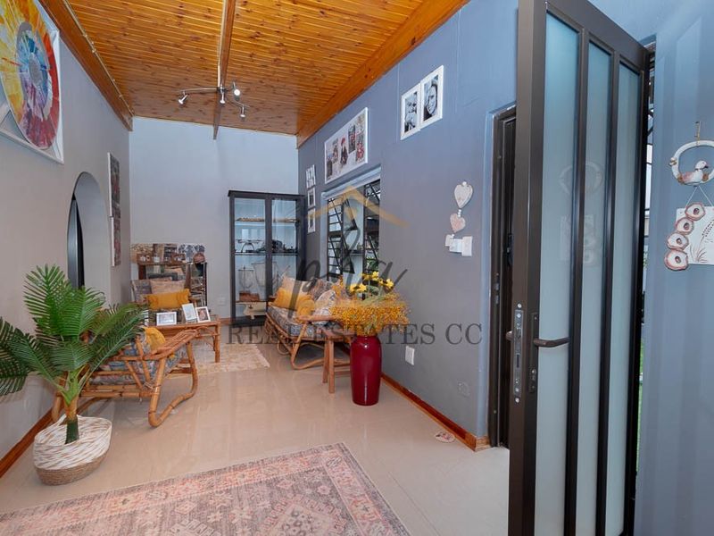 A living room featuring a warm timber ceiling, tiled flooring, and an arched entryway, providing a cozy and functional living space.