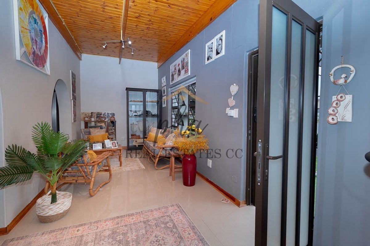 A living room featuring a warm timber ceiling, tiled flooring, and an arched entryway, providing a cozy and functional living space.