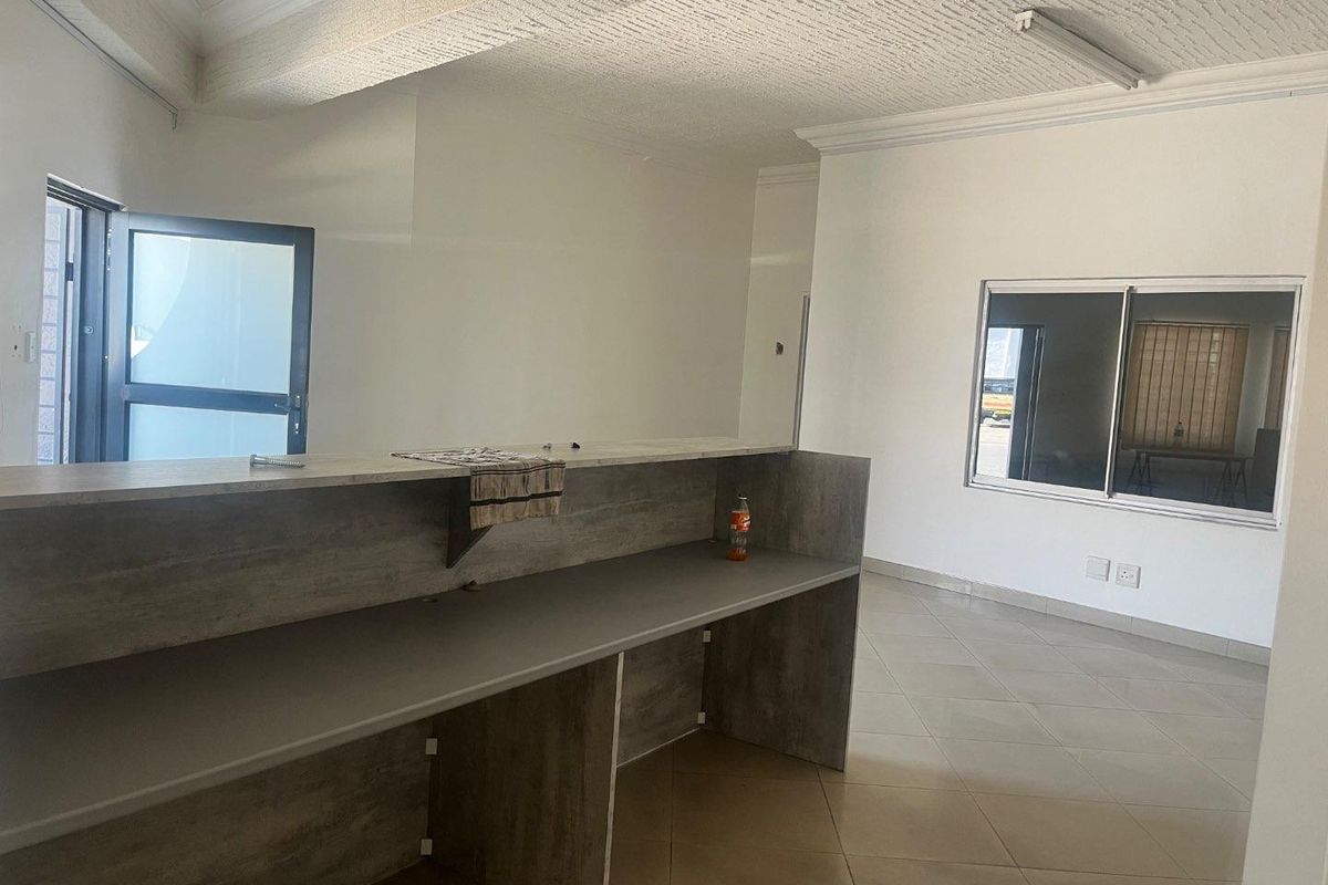 An open-plan interior space featuring tiled flooring, a built-in counter, and a textured ceiling, suitable for a variety of commercial or residential uses.