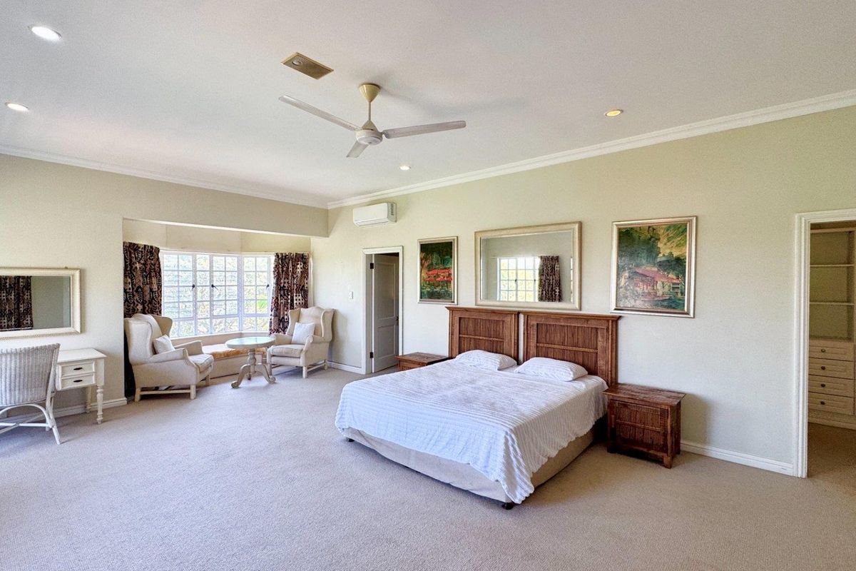 Spacious master bedroom featuring a bay window seating area, built-in wardrobe, ceiling fan, and split system air conditioning.