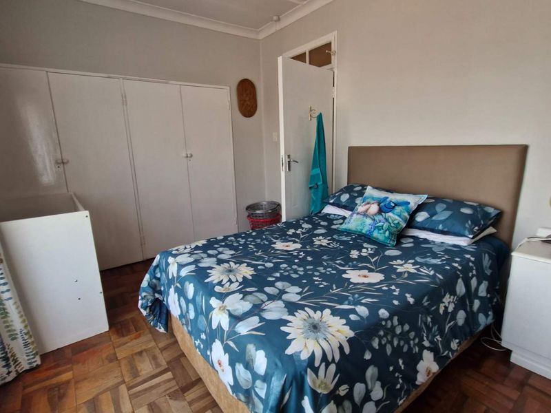A bedroom featuring classic parquet flooring, built-in storage cupboards, and coved cornicing, offering a functional and well-maintained living space.