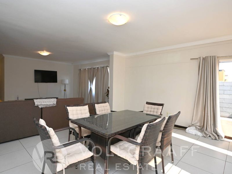 Open plan living and dining area featuring neutral tiled flooring and direct access to an outdoor space through a sliding glass door.