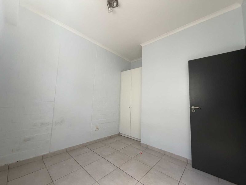 An empty bedroom featuring tiled flooring, a built-in wardrobe, and a neutral color palette, ready for personalization.