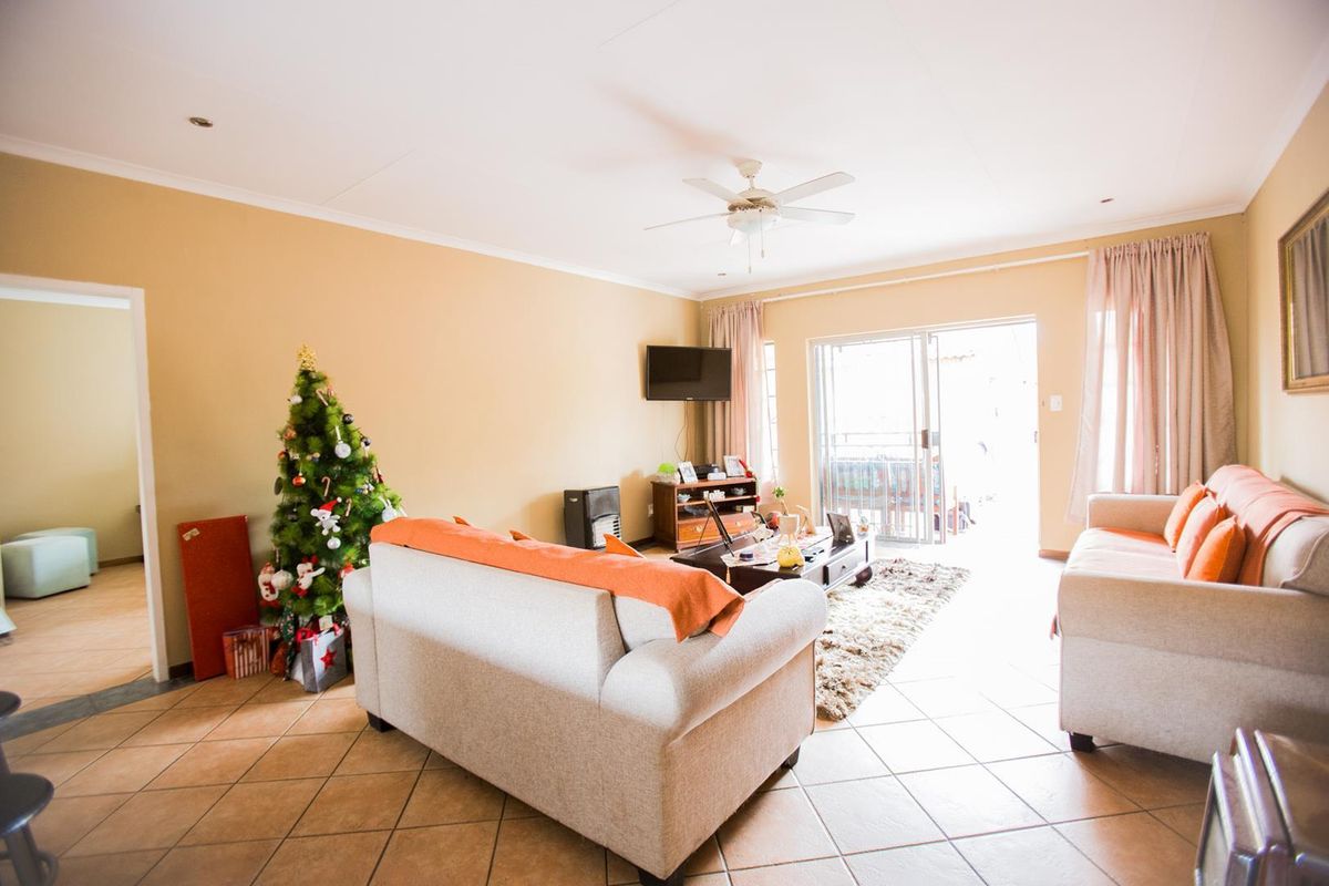 A spacious living room featuring tiled flooring, a ceiling fan, and sliding glass doors that provide access to the outdoor area.