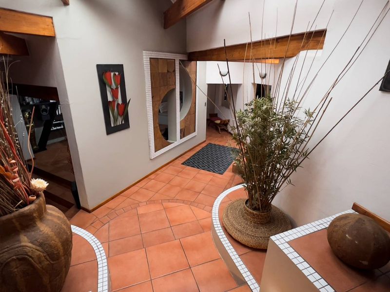 Spacious entrance hall featuring terracotta floor tiles, exposed timber ceiling beams, and unique built-in tiled planter boxes.
