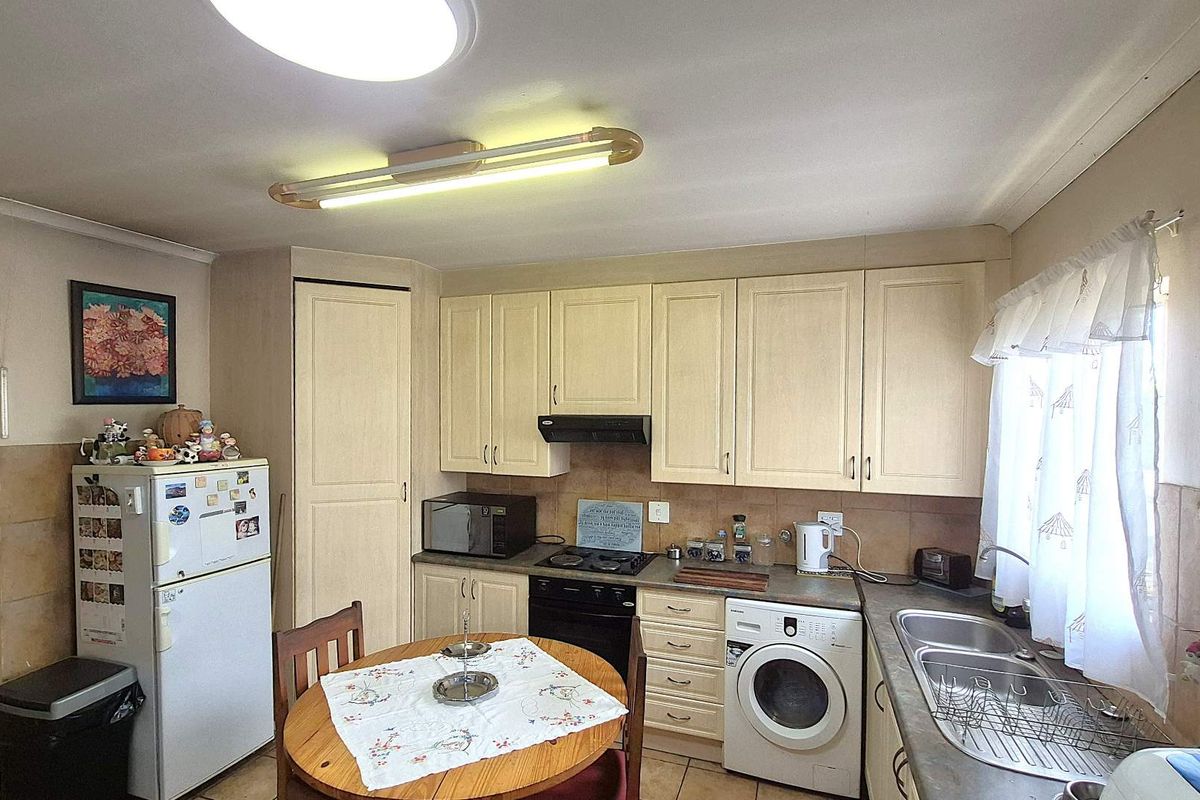 Functional kitchen featuring light-toned cabinetry, built-in oven with extractor fan, double basin sink, and integrated space for laundry appliances.