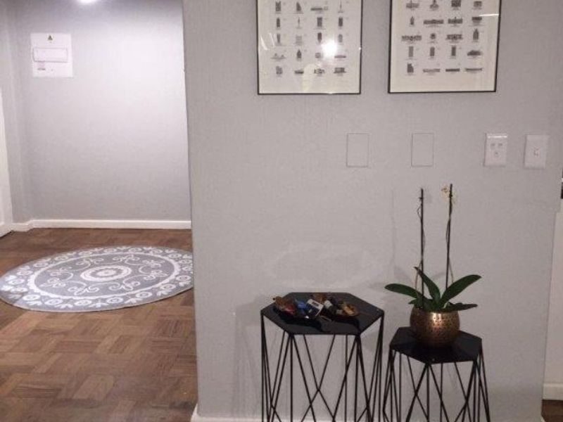 A well-maintained hallway featuring classic parquet flooring and a modern pendant light fixture, creating a clean and welcoming transition space.
