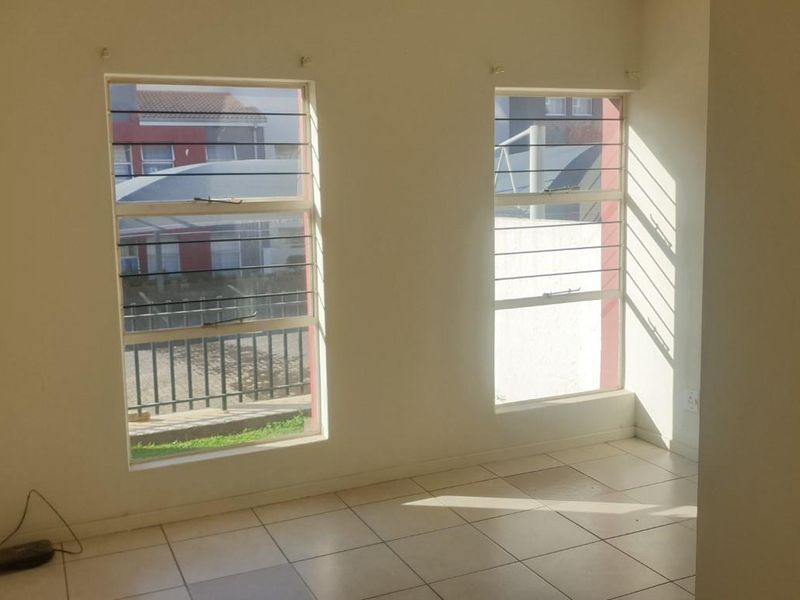 An empty bedroom featuring tiled flooring and windows fitted with security bars, offering a blank canvas for personalization.