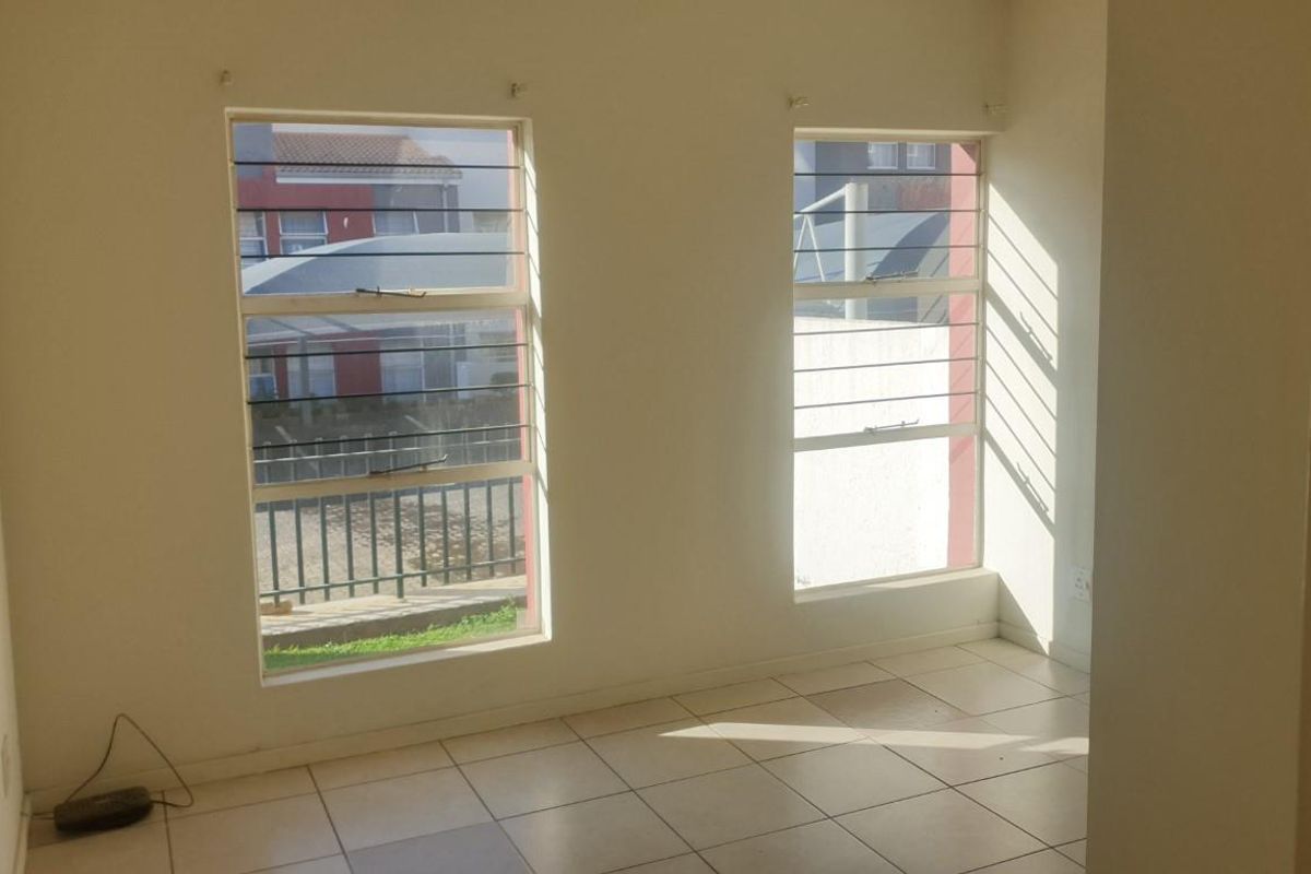 An empty bedroom featuring tiled flooring and windows fitted with security bars, offering a blank canvas for personalization.