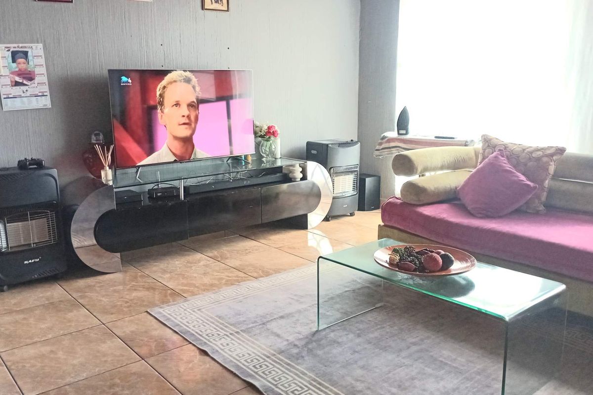 A living room featuring tiled flooring and a large window, providing a functional space for relaxation and entertainment.