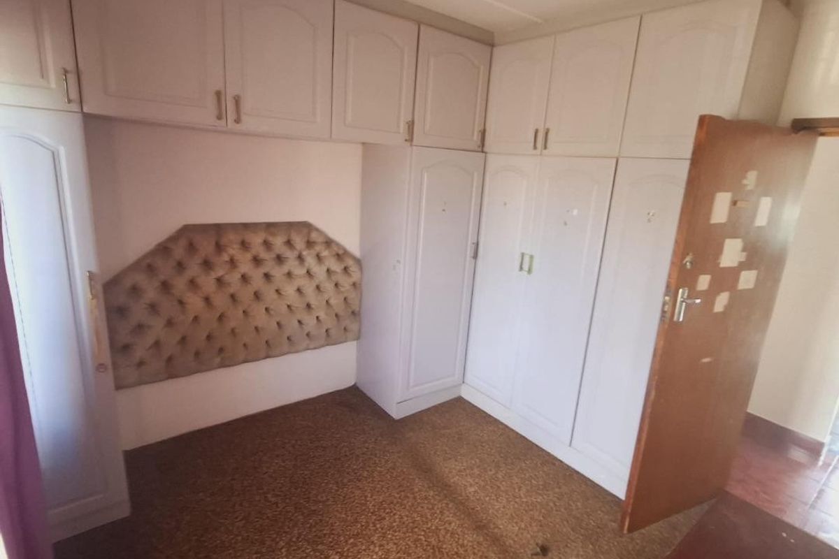 Bedroom featuring extensive built-in cabinetry with overhead storage and carpeted flooring, offering ample storage space in a functional layout.