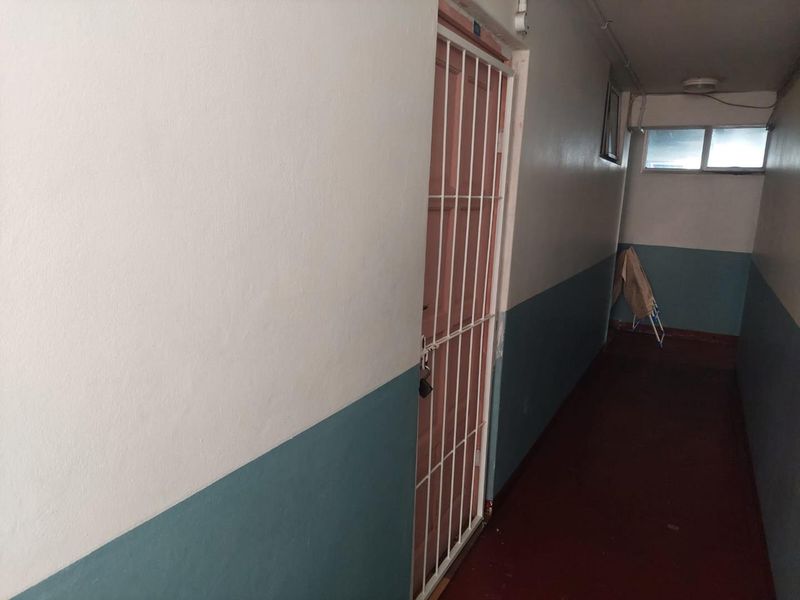 A functional apartment hallway featuring a security gate and two-tone wall paint, providing access to the unit entrance.