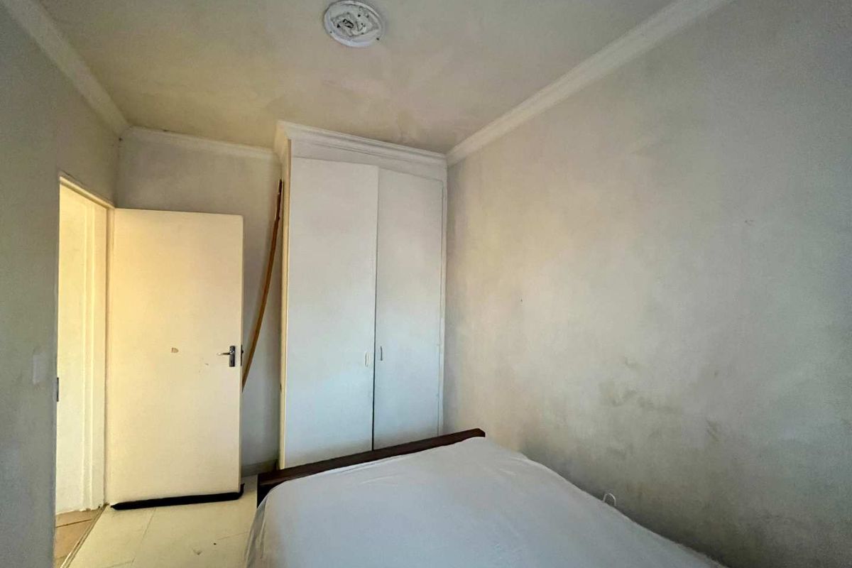 A bedroom featuring a built-in wardrobe and coving, currently requiring cosmetic updates to the walls and ceiling to improve its overall condition.