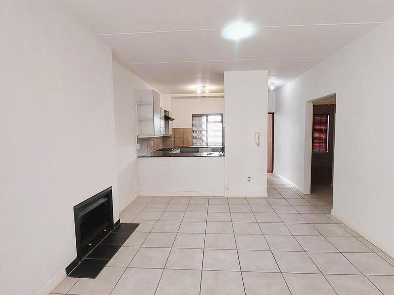 Open plan living area featuring tiled flooring, a built-in fireplace, and an adjoining kitchen space with fitted cabinetry.