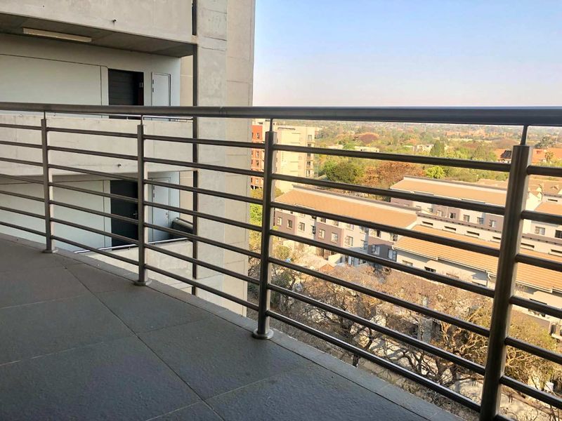 A spacious apartment balcony featuring durable tiled flooring and a modern stainless steel balustrade, offering elevated views of the surrounding neighborhood.