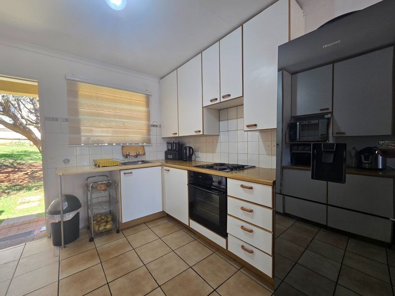 A functional kitchen featuring built-in cabinetry, a tiled backsplash, integrated oven and hob, and direct access to the outdoor area.