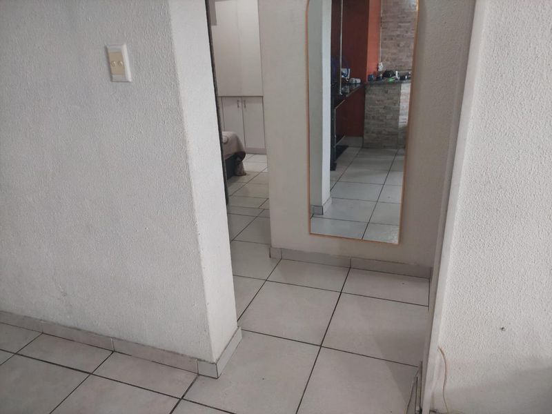 A functional hallway area featuring neutral ceramic floor tiles and white painted walls, providing access to adjacent living and bedroom spaces.