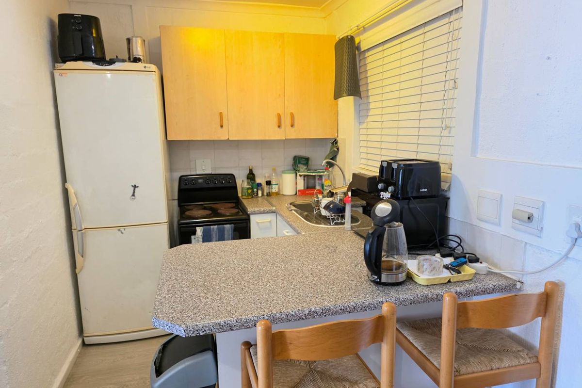 Compact kitchen featuring laminate countertops, wooden cabinetry, a built-in stove, and a breakfast bar area with integrated sink.