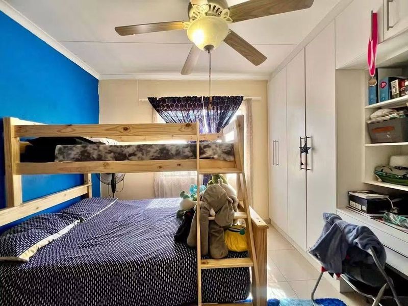 A bedroom featuring built-in cupboards, integrated shelving, tiled flooring, and a ceiling fan.