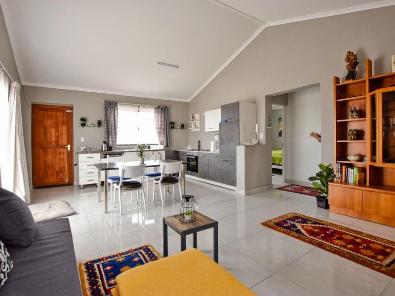Spacious open-plan living area featuring a modern kitchen with built-in cabinetry, tiled floors, and a vaulted ceiling, creating a bright and functional living space.