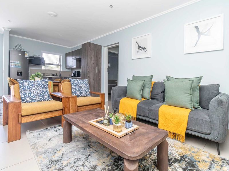 A bright open-plan living area featuring tiled flooring, recessed lighting, and a modern kitchen with built-in cabinetry, seamlessly connected to the living space.