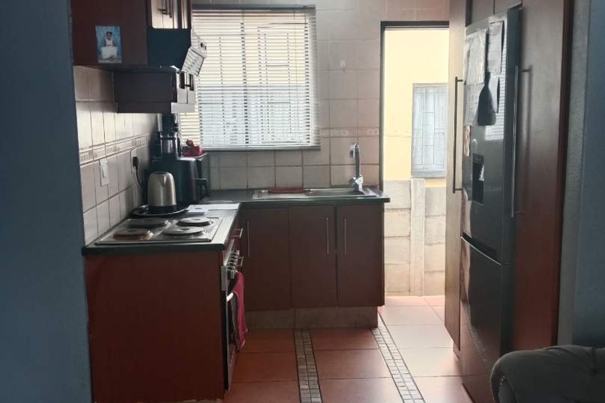 A functional kitchen featuring dark wood cabinetry, tiled backsplash, built-in stove, and direct access to an outdoor area.