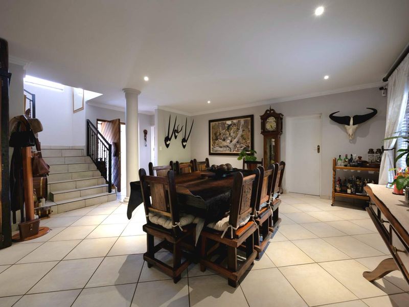 Spacious dining area featuring tiled flooring, recessed lighting, and an integrated staircase with a metal balustrade.