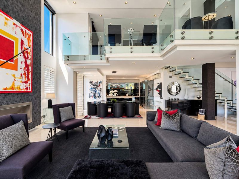 Spacious open-plan living and dining area featuring double-volume ceilings, a modern floating staircase with glass balustrades, and high-end contemporary finishes throughout.