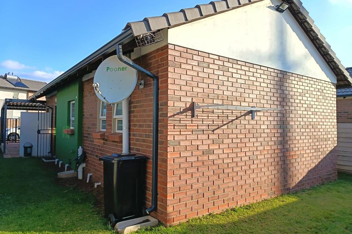 A view of the rear brick exterior of the house, featuring a satellite dish, wall-mounted clothesline, and functional guttering system.