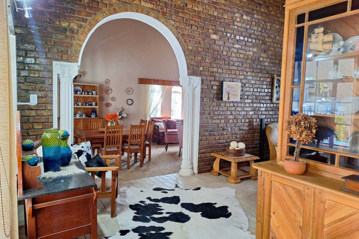 Spacious living area featuring a prominent exposed brick wall and a decorative arched entryway leading into the adjacent dining room.