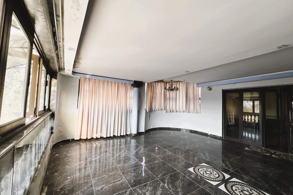 Spacious living area featuring polished dark marble flooring, a structural column, and large windows with integrated curtain tracks.