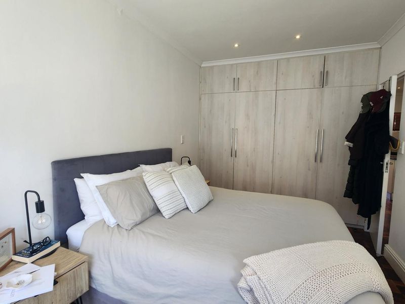 A well-maintained bedroom featuring neutral walls, recessed downlighting, and extensive built-in cabinetry for storage.