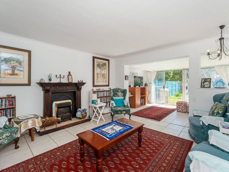 Spacious living room featuring a traditional fireplace with a wooden mantelpiece, tiled flooring, and sliding glass doors providing access to the rear garden.