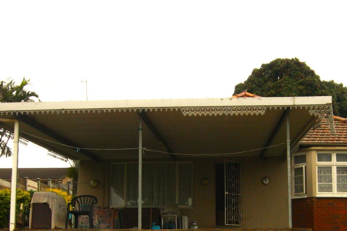 Rear view of the property featuring a covered patio area, brick bay window, and tiled roof structure.