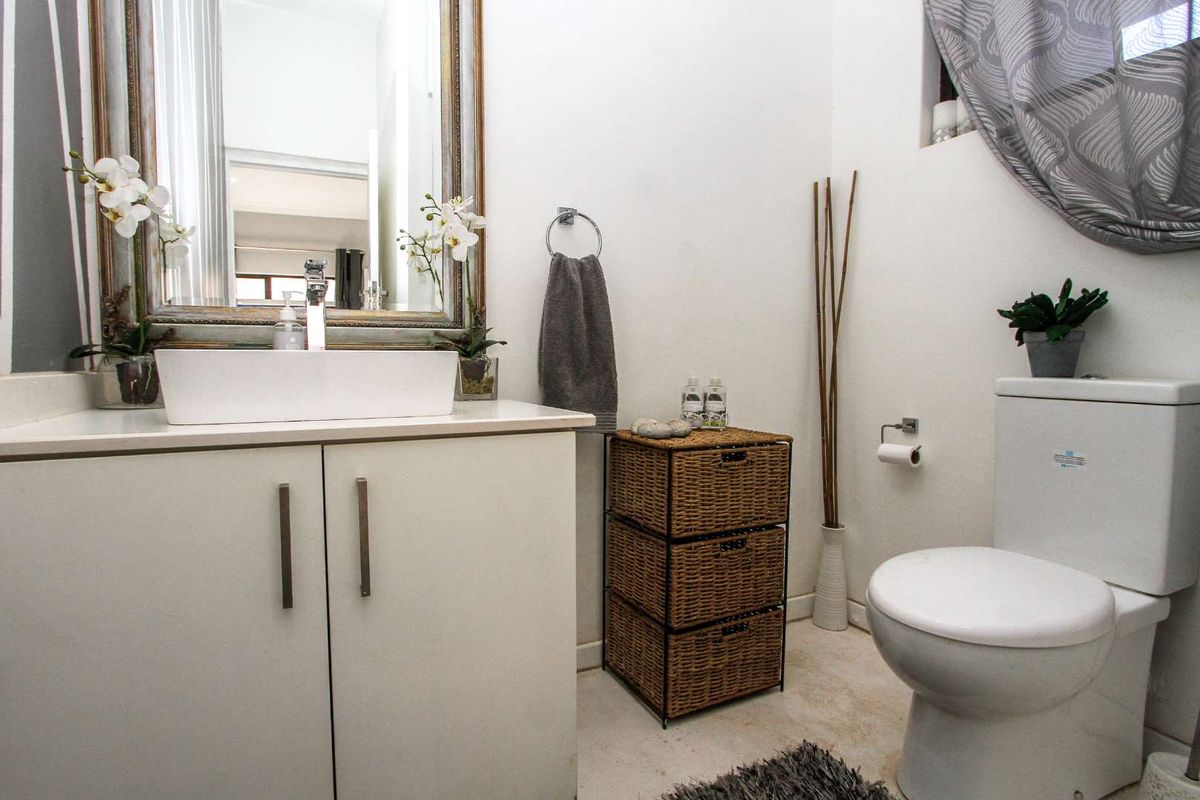 A compact bathroom featuring a modern vessel sink vanity, a wall-mounted mirror, and a standard toilet.