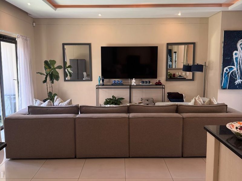 Spacious open-plan living area featuring modern tiled flooring, recessed ceiling lighting with cove accents, and large sliding glass doors leading to the exterior.