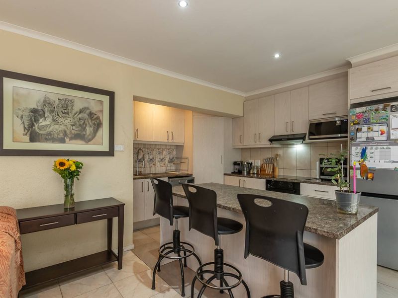 Open-plan kitchen featuring light wood cabinetry, granite countertops, a breakfast bar, and integrated appliances, seamlessly flowing into the adjacent living area.