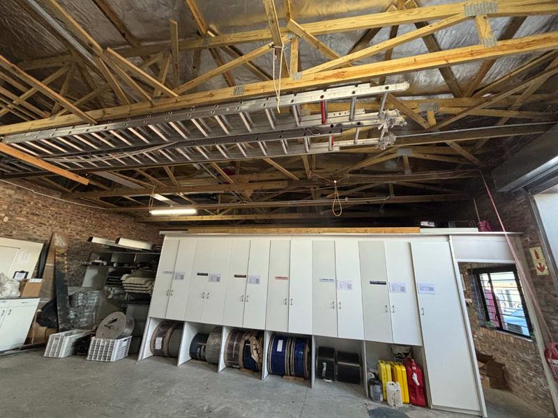 A spacious utility or storage area featuring exposed timber roof trusses, concrete flooring, and extensive built-in cabinetry for organized storage.