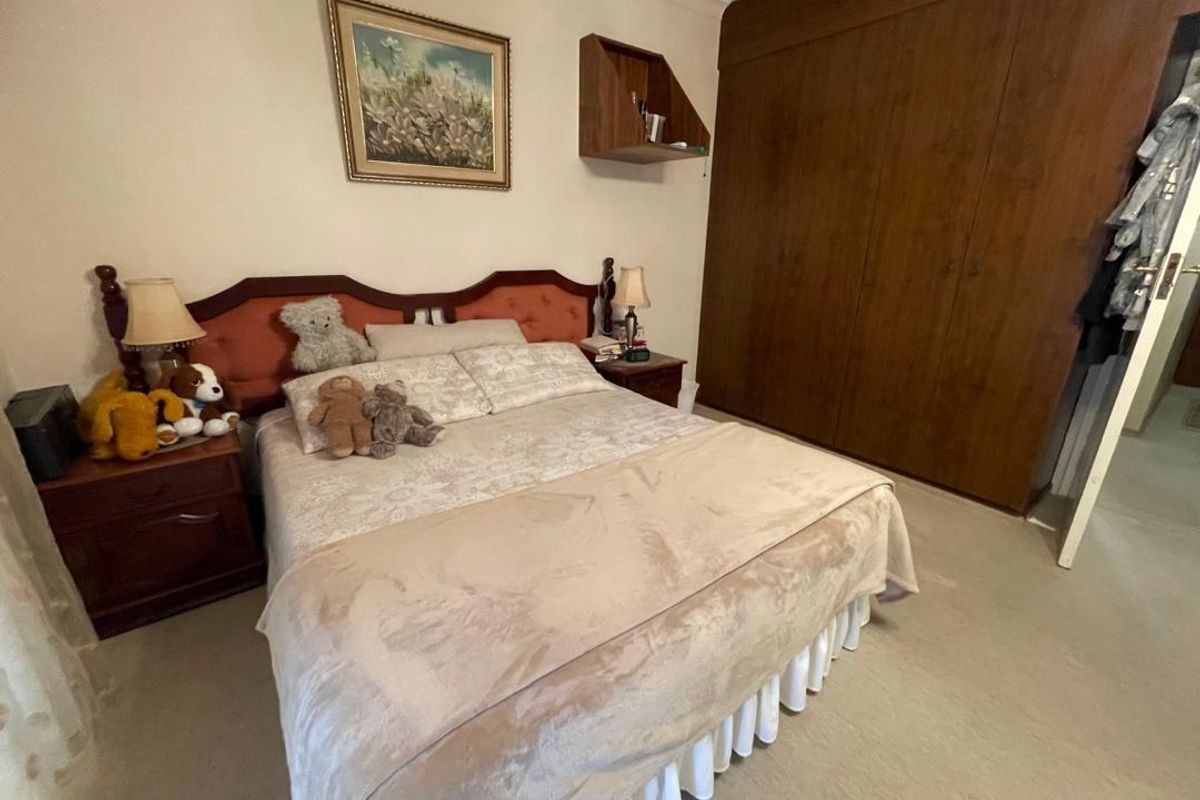 A bedroom featuring built-in wooden wardrobes and neutral carpeting, offering a functional space with traditional finishes.