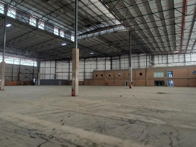 Expansive industrial warehouse space featuring high ceilings, exposed steel trusses, durable concrete flooring, and integrated fire safety systems.