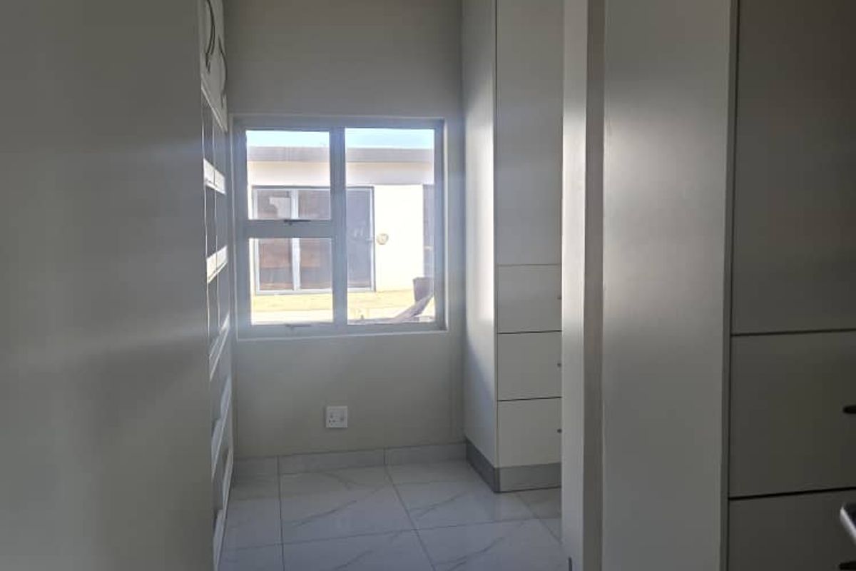 A bright, modern walk-in closet or bedroom area featuring sleek white built-in cabinetry, polished marble-look floor tiles, and clean contemporary finishes.