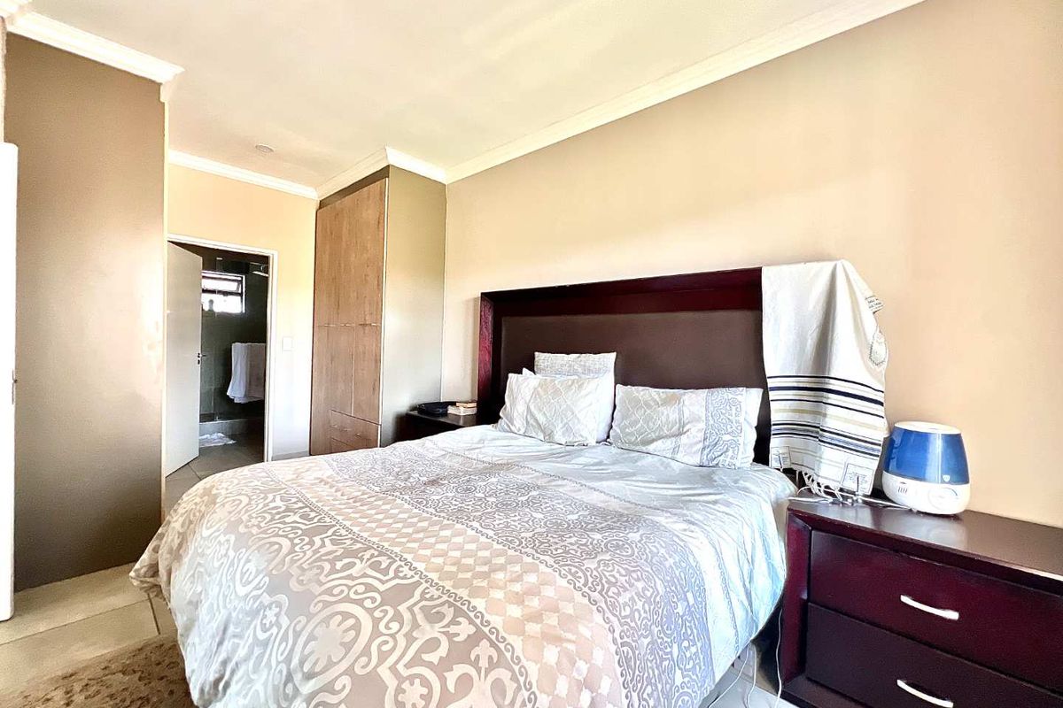 A bedroom featuring built-in wooden cabinetry and an en-suite bathroom entrance, finished with neutral wall tones and crown molding.