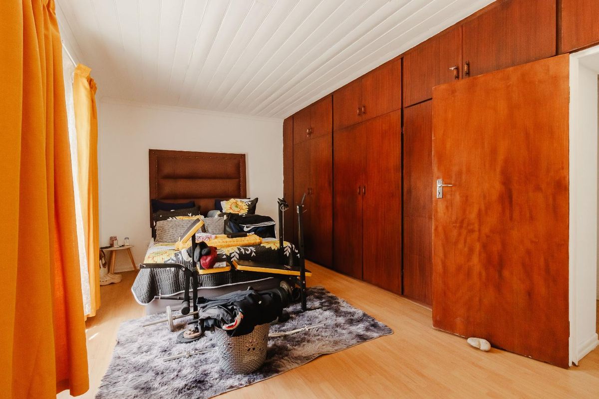 A bedroom featuring extensive built-in wooden cabinetry, laminate flooring, and a white tongue and groove ceiling.