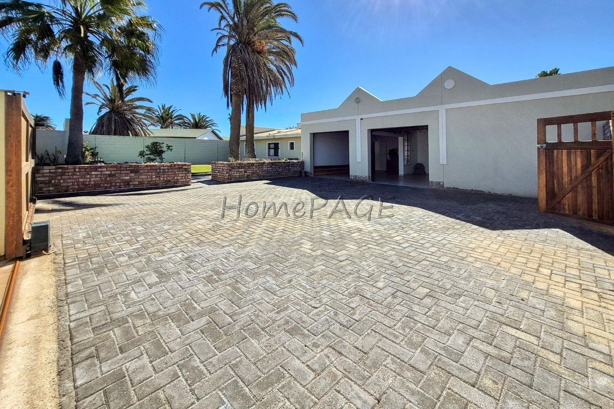 Spacious paved driveway and courtyard area featuring brick planter boxes and access to a double garage.