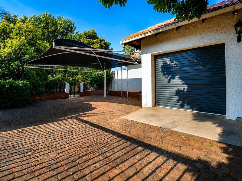 Exterior view of the property featuring a paved driveway, a roller garage door, and a shade sail carport structure.