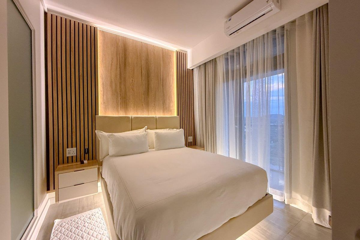 Modern bedroom featuring a decorative timber slat feature wall with integrated LED accent lighting, tiled flooring, and a wall-mounted air conditioning unit.