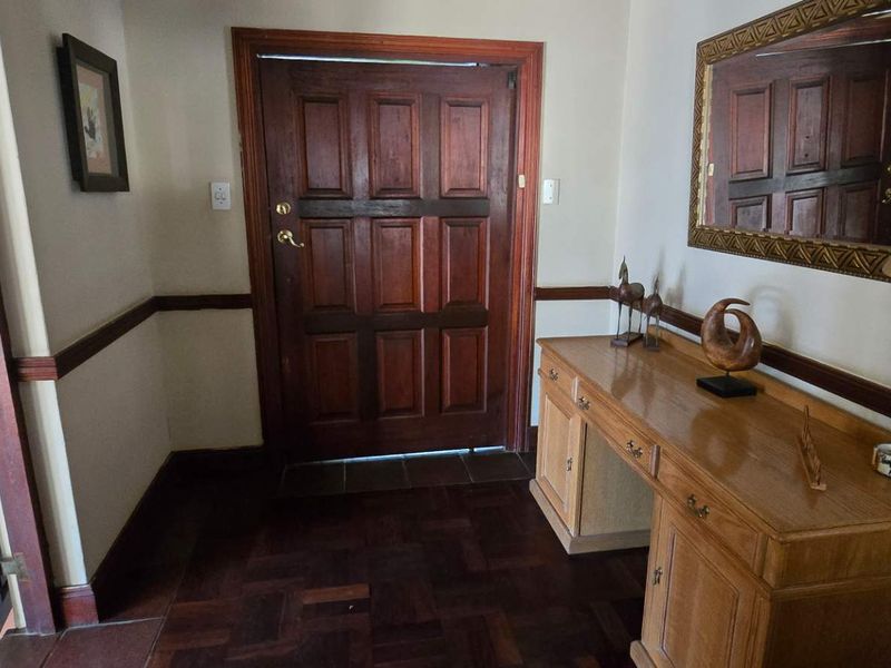 Welcoming entrance hall featuring classic wooden parquet flooring and a solid timber panelled front door, providing a warm and traditional first impression.