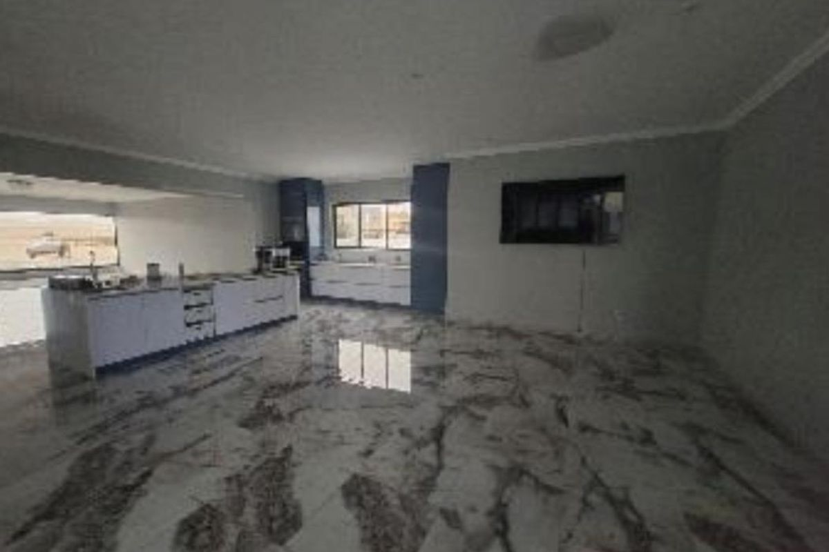 Spacious open-plan living and kitchen area featuring polished marble-look floor tiles, modern built-in cabinetry, and a central kitchen island.