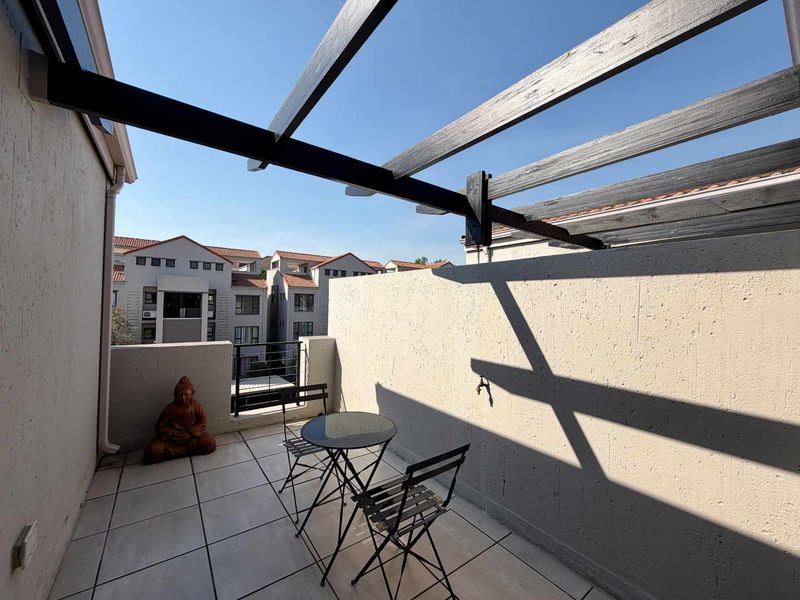 A private balcony featuring tiled flooring, a timber pergola structure, and an external wall tap, offering an open-air outdoor living space.