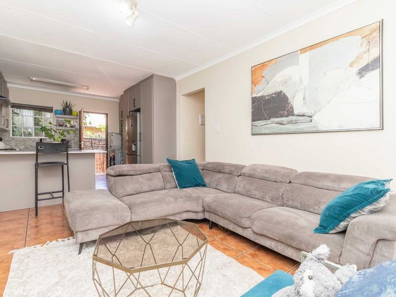 An open-plan living area featuring a modern kitchen with built-in cabinetry and a breakfast island, seamlessly flowing into the lounge space with tiled flooring.